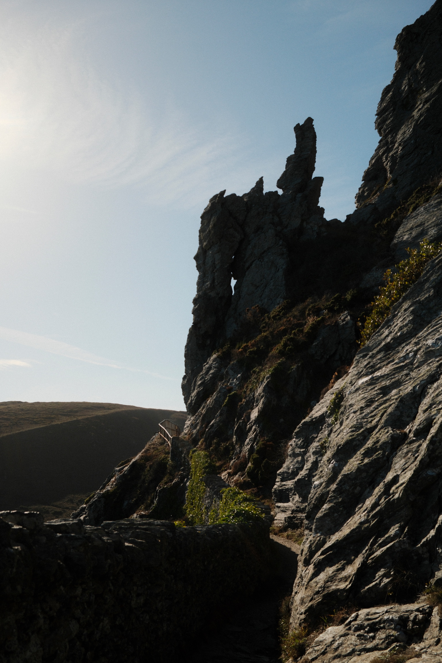 A dark rock face opens toward a sunlit slope and sky