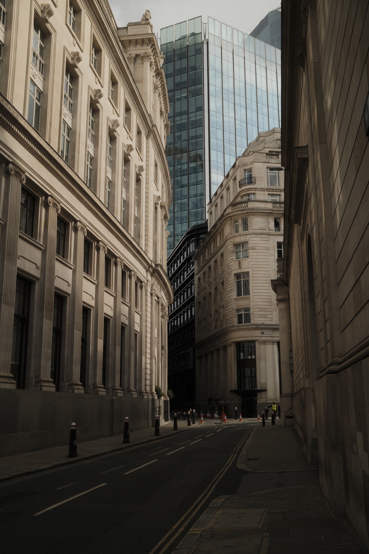 A narrow city street leads toward a glass tower