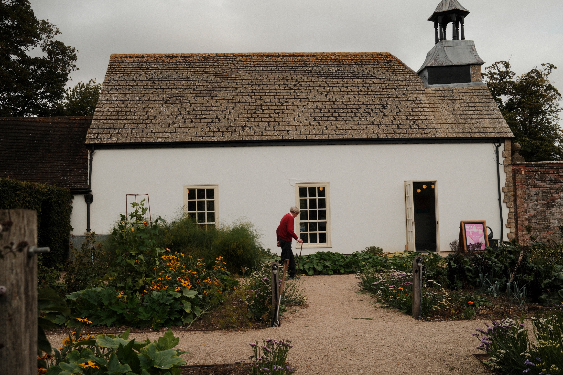 A person tends a garden outside a white cottage