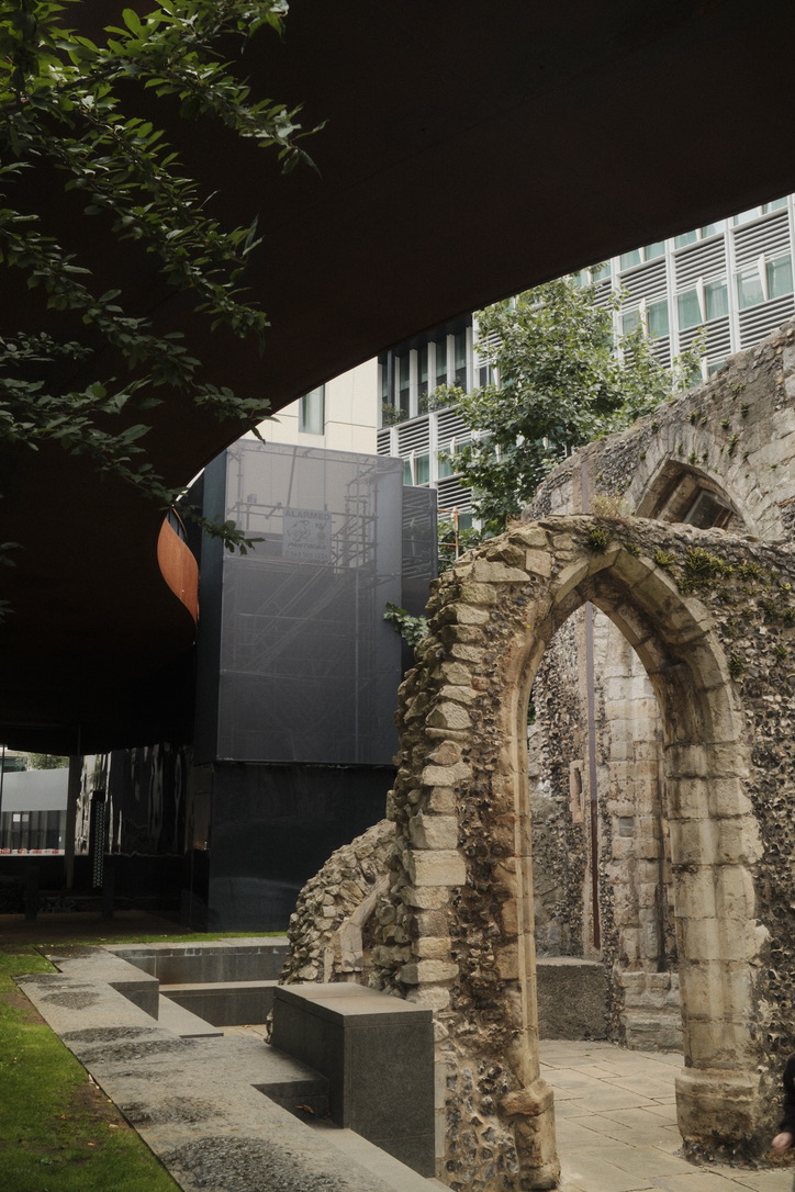 A historic stone arch stands beneath modern concrete and glass
