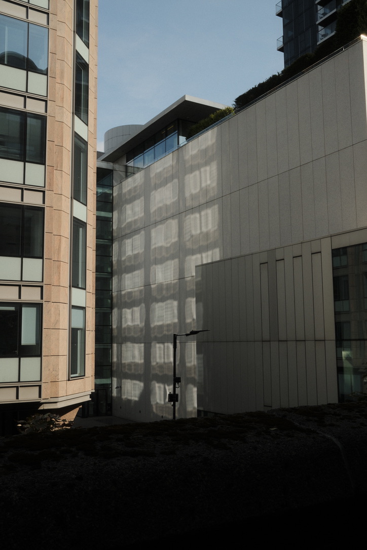 A grid of sunlight falls across a pale building facade