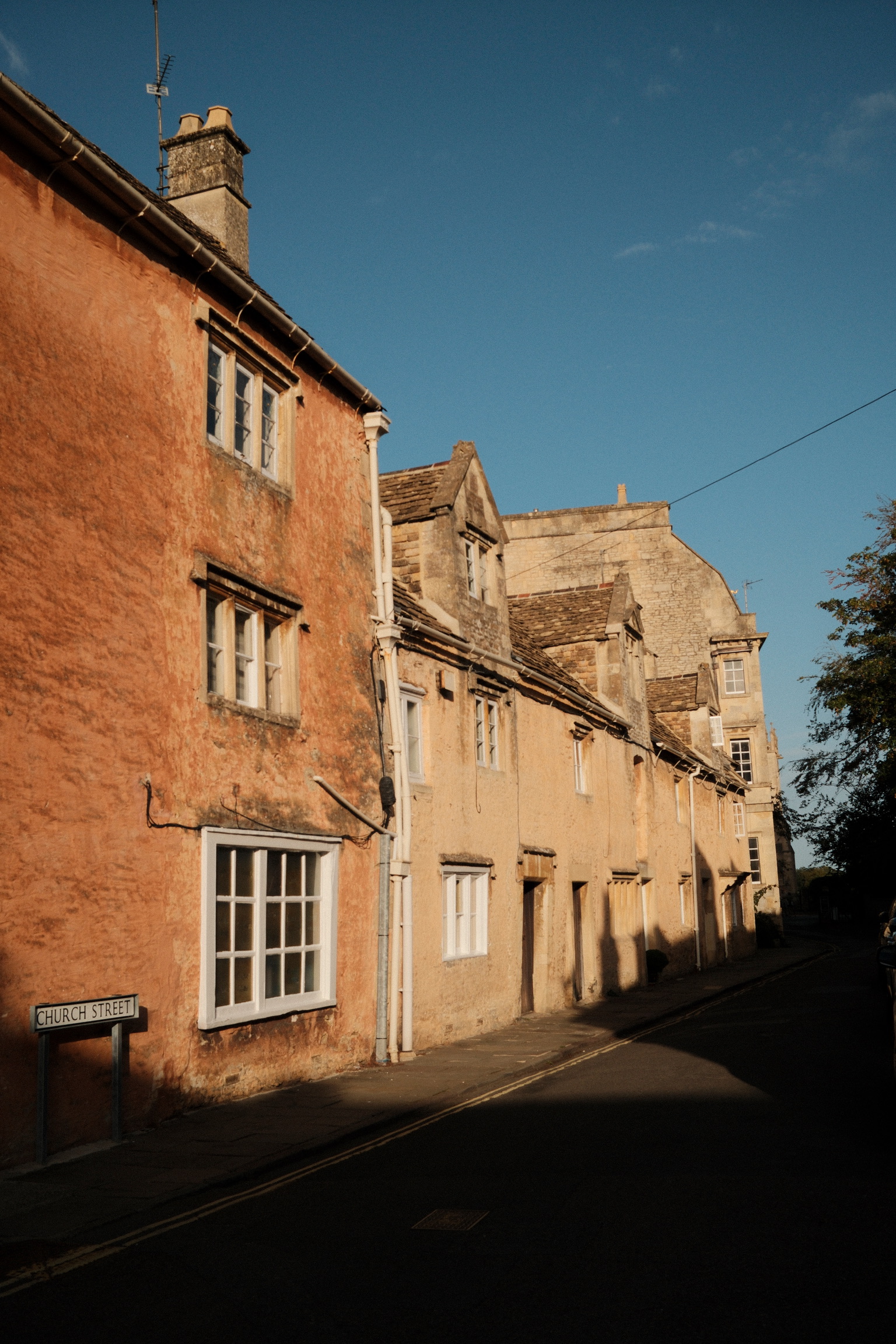Warm stone houses meet a diagonal field of afternoon shadow
